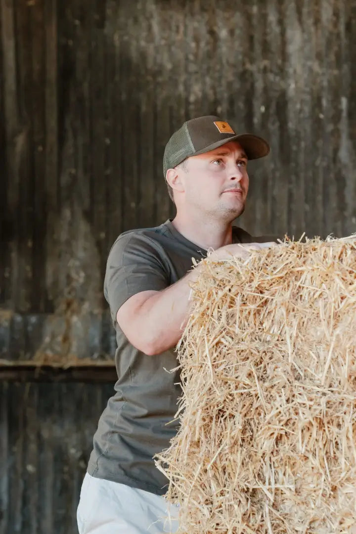Man holding hay bale wearing New Forest Logo T-Shirt with forest clothing graphic