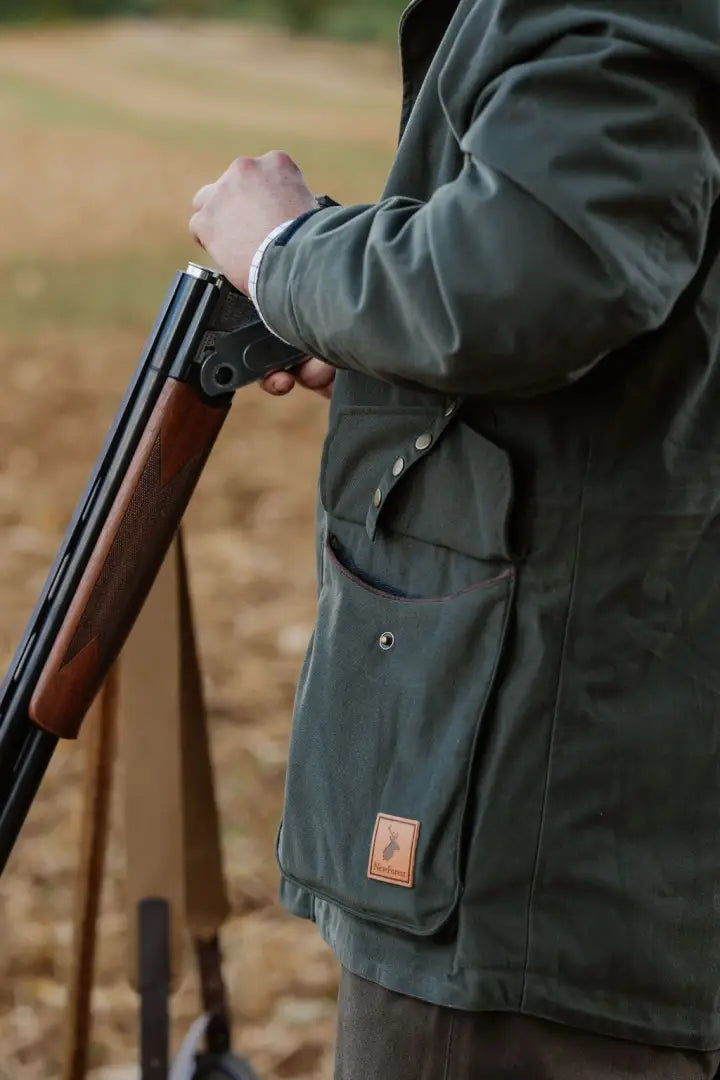 Hunter in olive green Forest Marsh Jacket loading shotgun outdoors