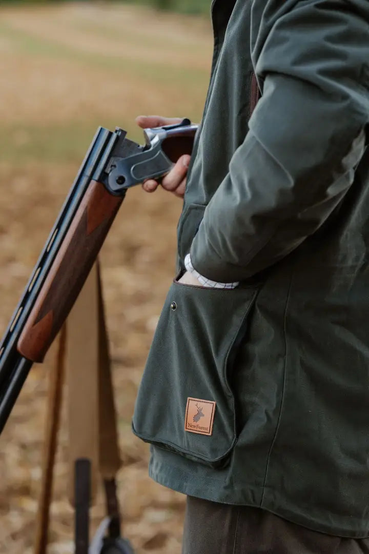 Person in a hunting jacket holding a shotgun wearing the New Forest Marsh Jacket