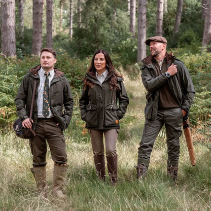 Three people in hunting attire wearing the New Forest Marsh Jacket in forest marsh area