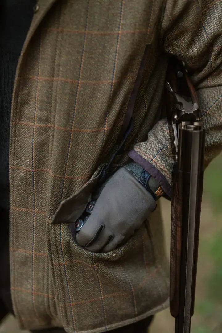 Person in a New Forest Maverick Waterproof Tweed Jacket with gloves holding a shotgun