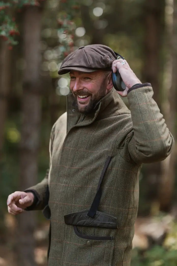 Smiling man in New Forest Maverick waterproof tweed jacket with ear protectors
