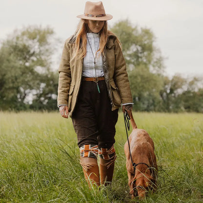Woman in country attire walking a dog in grassy field wearing New Forest Moleskin Breeks
