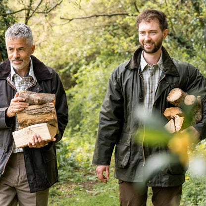 Two men outdoor adventuring in a Padded Wax Jacket while carrying firewood