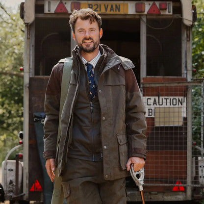 Man with beard in dark jacket holding tool, showcasing New Forest Performance Field Coat