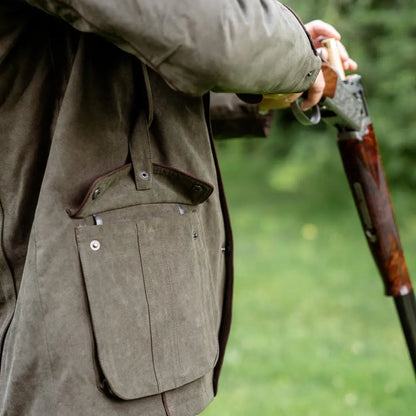 Person in hunting jacket holding a shotgun showcasing the New Forest Performance Field Coat