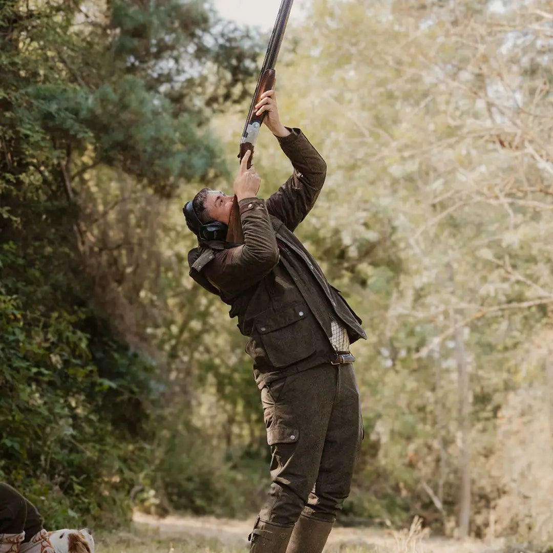 Person in hunting attire holding a shotgun with New Forest Performance Field Coat