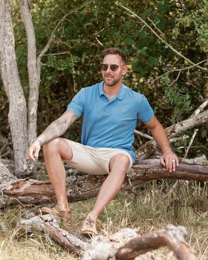 Man wearing New Forest Pique Polo Shirt in blue polo and khaki shorts
