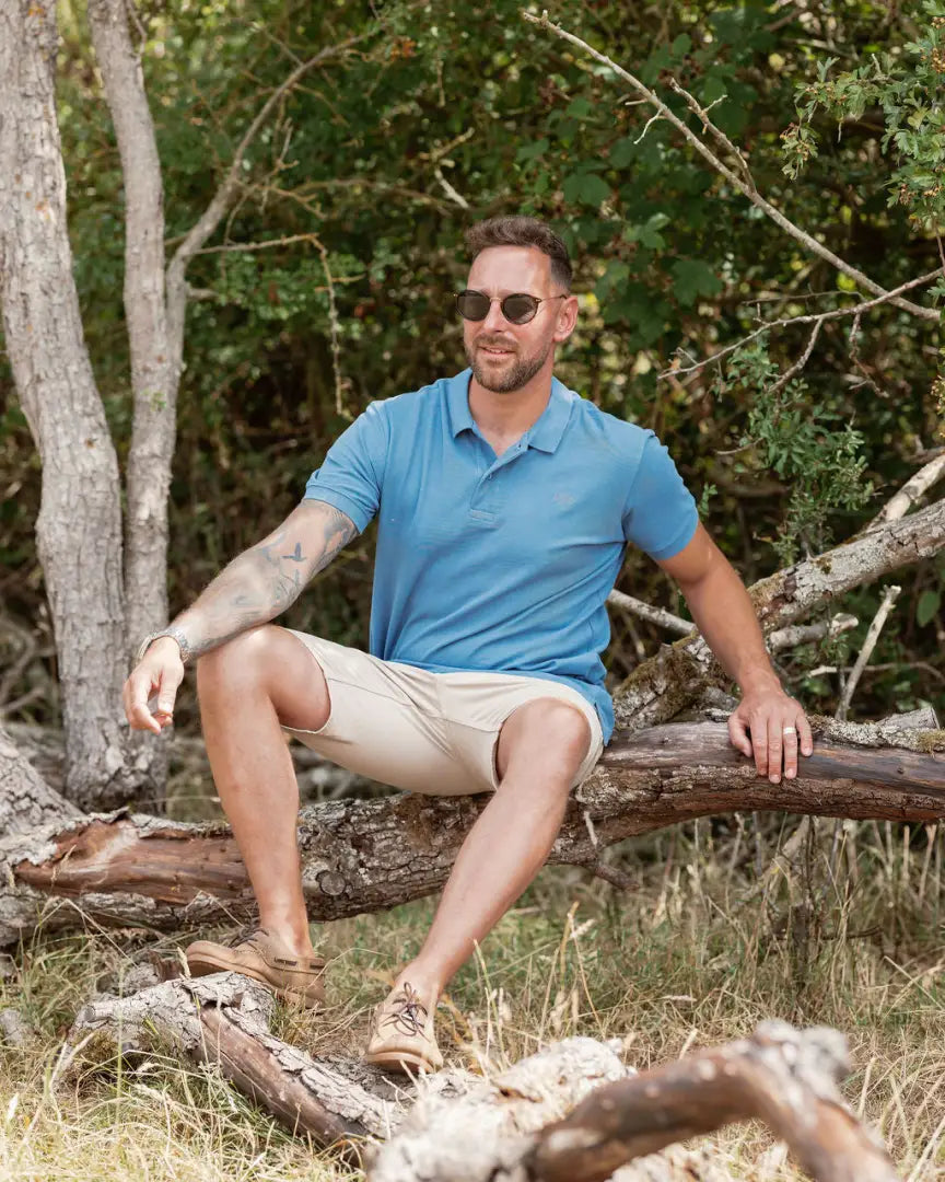 Man wearing New Forest Pique Polo Shirt in blue polo and khaki shorts