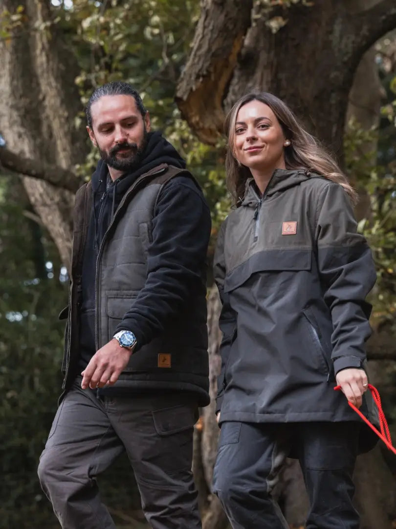 Two people in outdoor gear walking through woods wearing the New Forest Polar Gilet