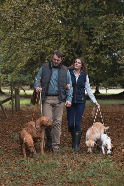 Couple walking four dogs in autumn forest wearing New Forest Polar Gilet for warmth