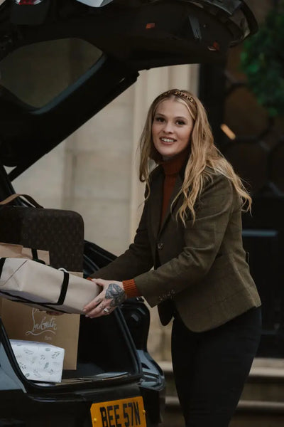 Woman loading car trunk while wearing a stylish Polly Tweed Blazer