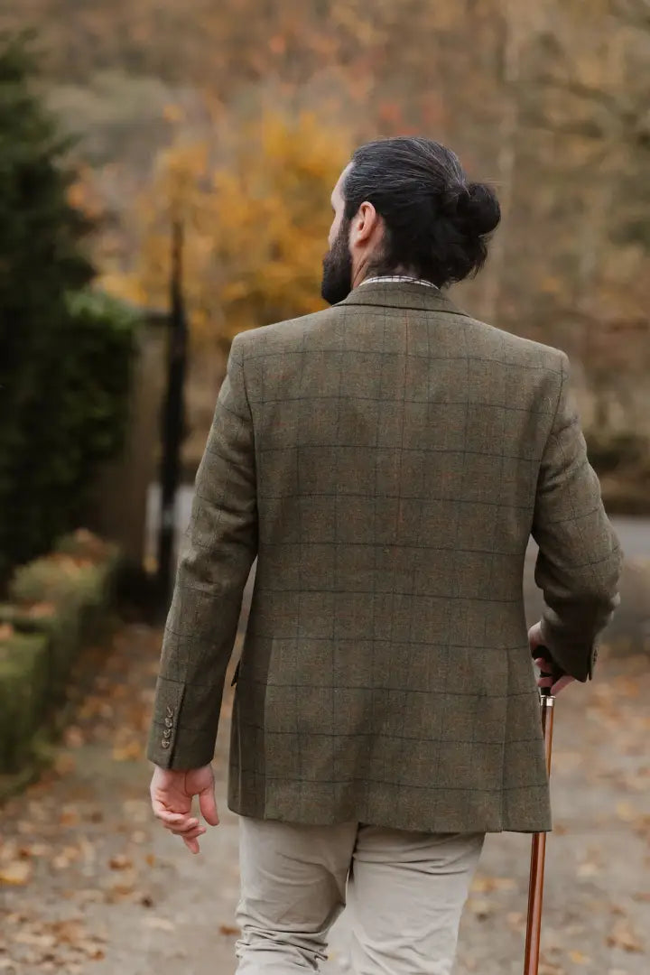 Man with beard in green wool tweed waistcoat holding a walking stick outdoors