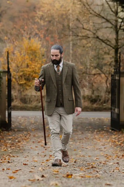 Man in a three-piece wool tweed fabric waistcoat holding a walking stick