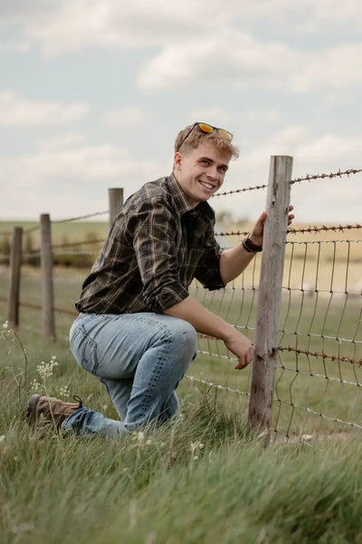Smiling man in New Forest Premium Tattersall Shirt with single chest pocket by barbed wire