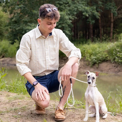 Man kneeling by water with small white dog wearing New Forest Premium Tattersall Shirt