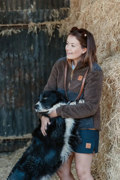 Woman hugging a black and white dog in New Forest Rugby Shorts, perfect for country clothing and hunting fun