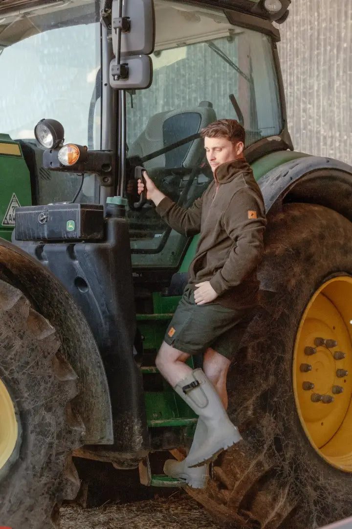 Man climbing into tractor wearing New Forest Rugby Shorts, perfect country clothing for hunting
