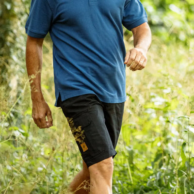 Person in blue shirt and black forest trail shorts enjoying a walk outdoors