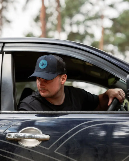 Man wearing a New Forest Trucker Hat with rugged charm driving a car
