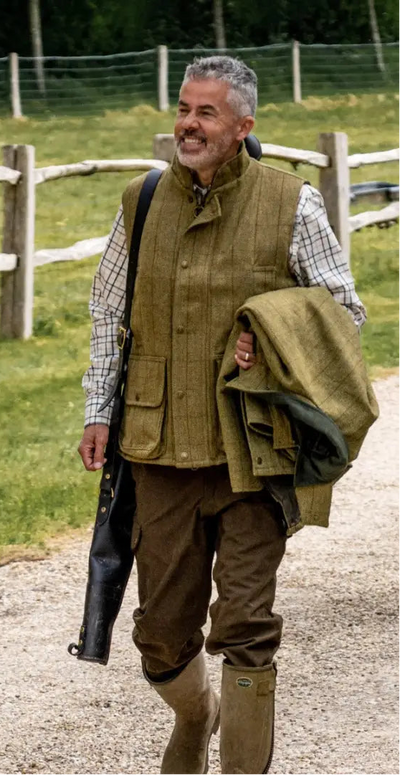 Two people in a luxurious tweed gilet stroll down a country path