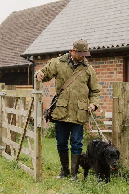 Man in a tweed shooting jacket enjoying time outdoors with his dog