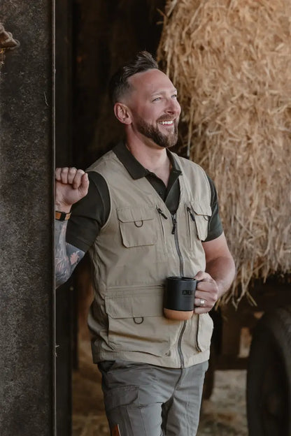 Smiling man wearing New Forest V-Neck Explorer Gilet holding coffee mug outdoors