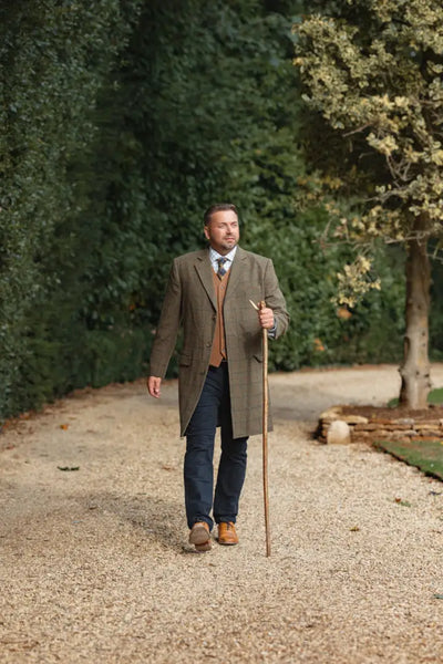 Man in tweed overcoat and forest wool mix waistcoat holding walking stick
