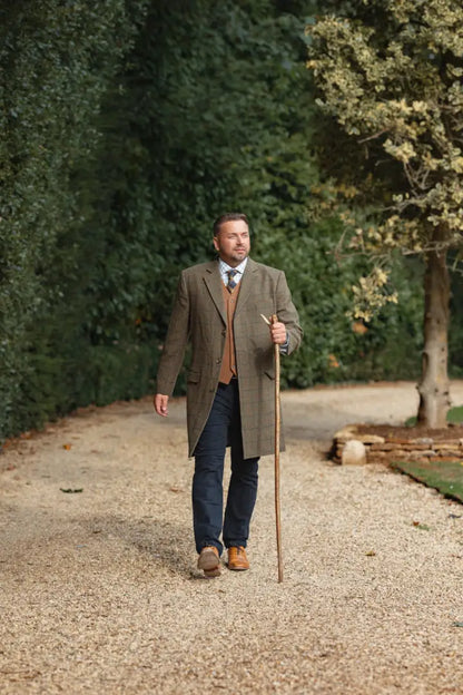 Man in tweed overcoat and forest wool mix waistcoat holding walking stick