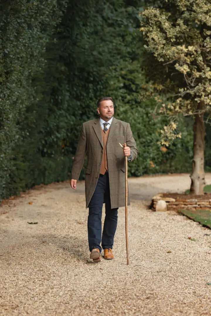 Man in tweed overcoat and forest wool mix waistcoat holding walking stick
