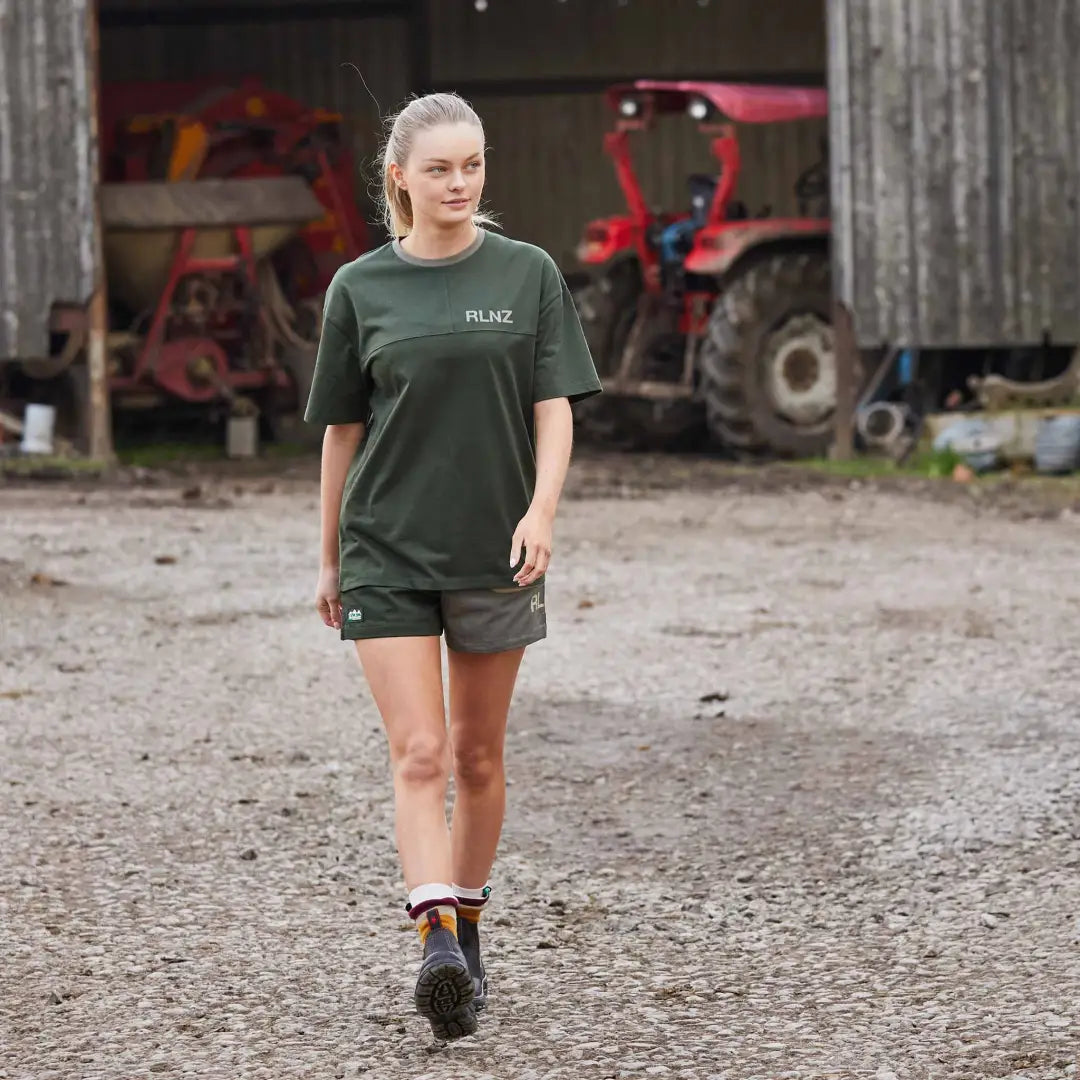 Young woman in green t-shirt and shorts on dirt path, perfect for country clothing and outdoors