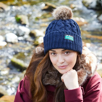 Woman wearing a dark blue Ridgeline Nordic Fleck Bobble Hat with fur pom-pom