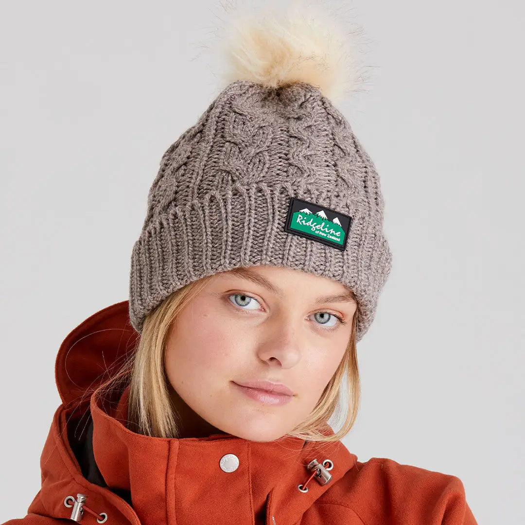 Gray Nordic Fleck Bobble Hat with fluffy pom-pom and green black label