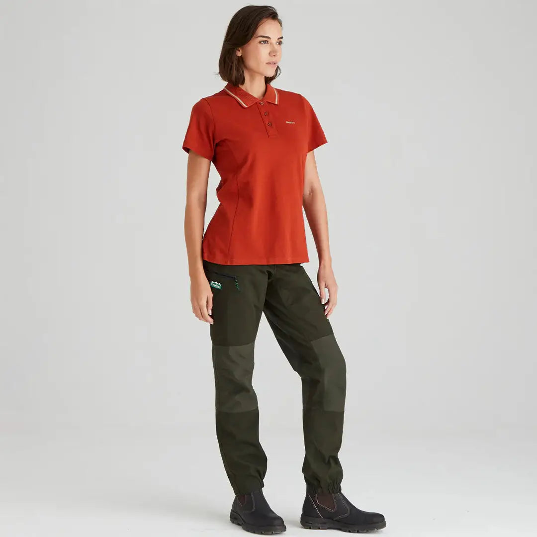 Woman wearing stylish rust-colored Kilworth Polo Shirt with dark green pants