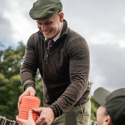 Smiling man holding clay targets wearing Seeland Benjamin Half Zip Fleece for outdoor fun