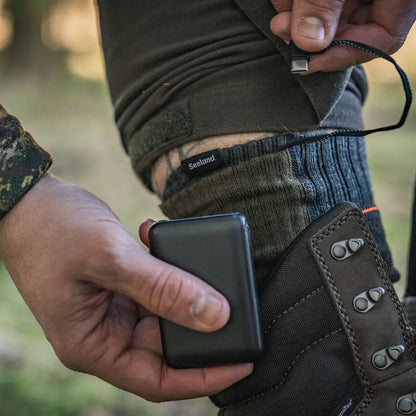 Person holding a portable charger next to a Seeland Celsius Heat Sock showing power banks for country clothing