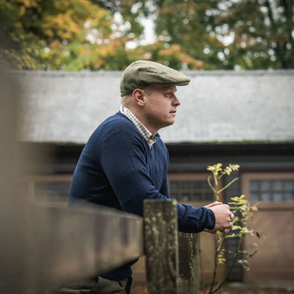 Man in tweed cap leaning on fence wearing Seeland Pine V-Neck Pullover, perfect country hunting gear