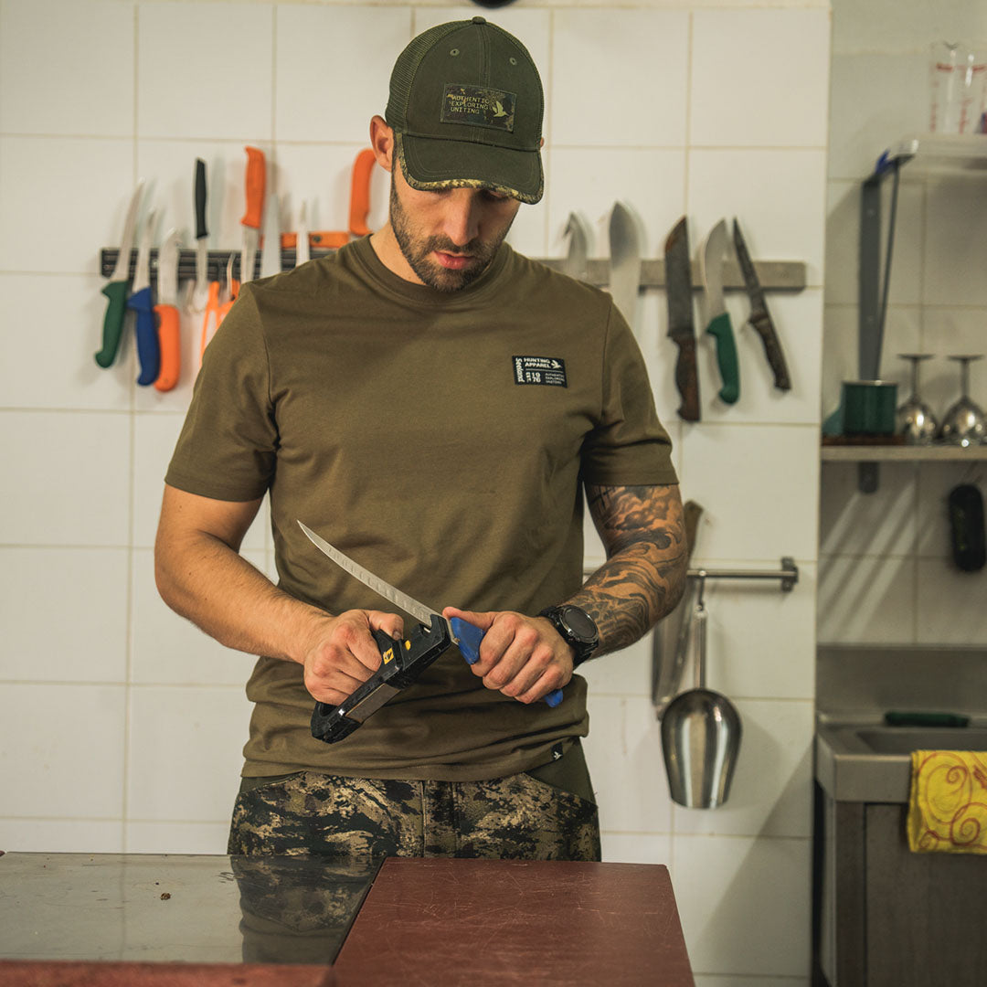 Man sharpening a knife in Seeland Striker T-Shirt, perfect for country clothing and hunting