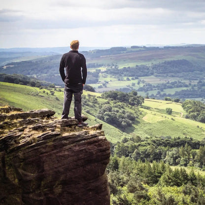 Person on a cliff wearing Snugpak Impact Fleece, enjoying a stunning valley view