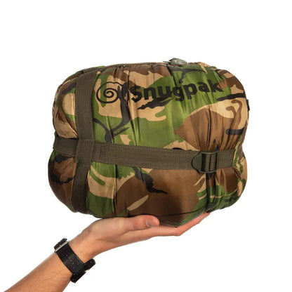 Hand holding a Camouflage Snugpak Sleeper Zero sleeping bag for camping adventures