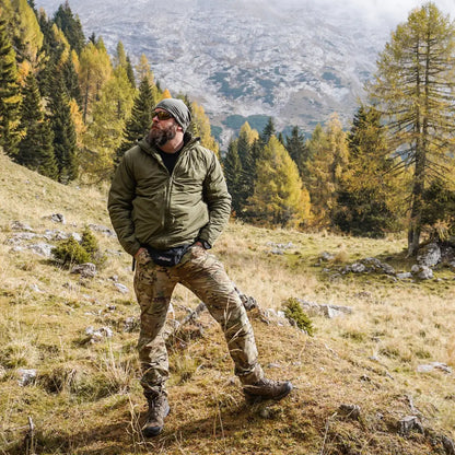 Hiker in Snugpak Spearhead Technical Midweight Insulated Jacket on a grassy mountain