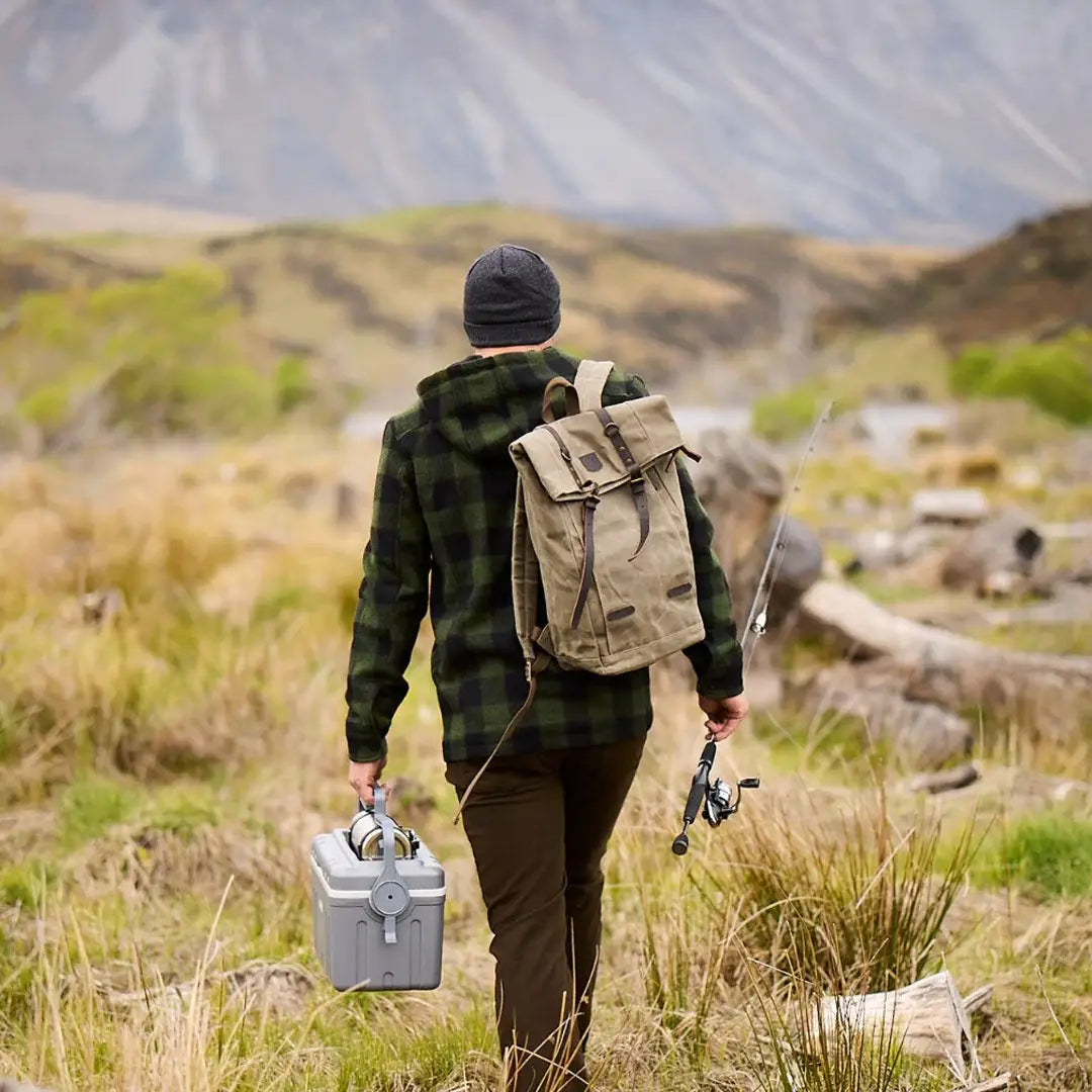 Person with Swanndri Arrowtown backpack fishing in a grassy field for country hunting gear