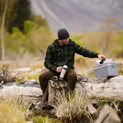 Person in a Hudson Wool Hoody relaxing on a log with a thermos and cooler
