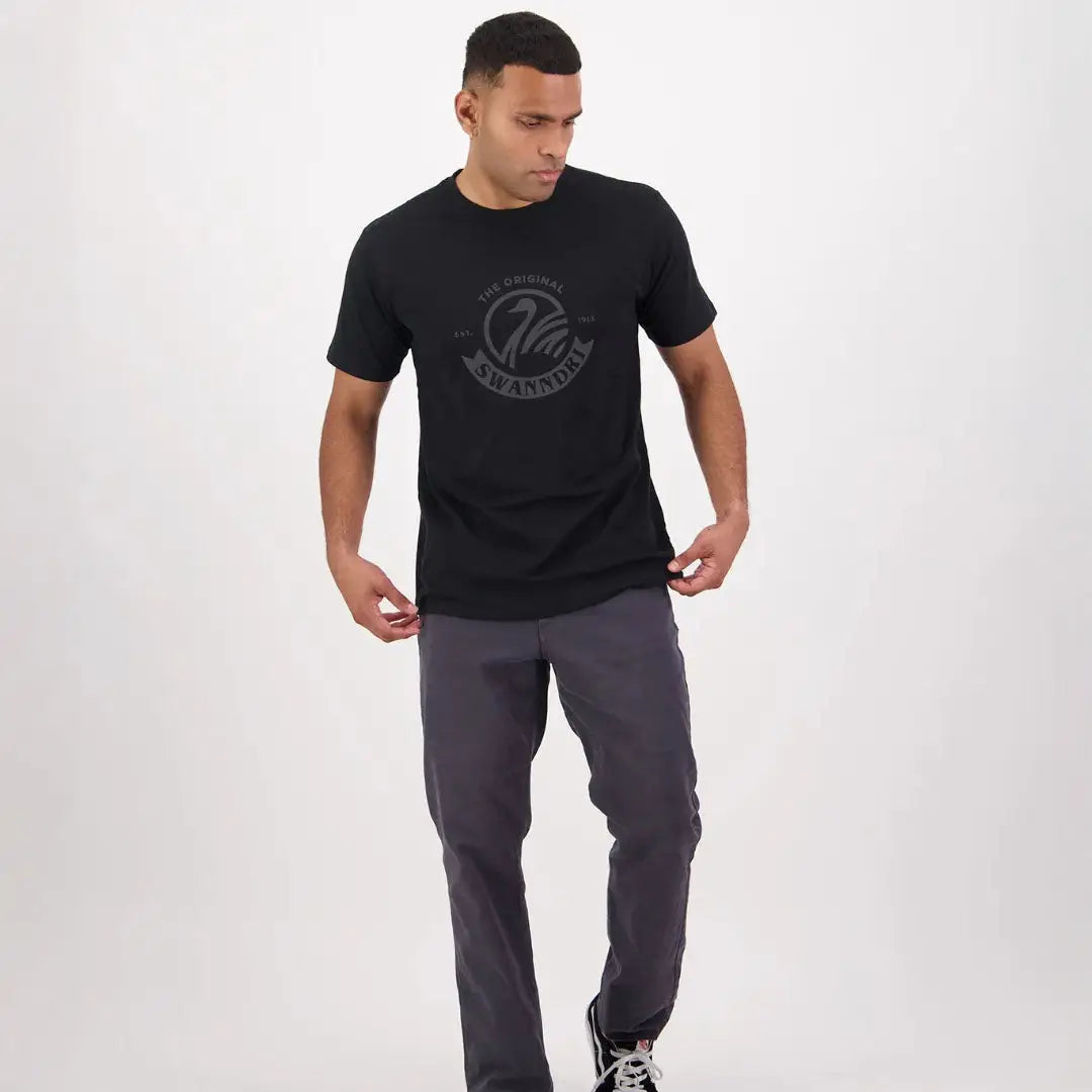 Man in a black t-shirt and gray pants showcasing the Swanndri Original V2 Printed Tee