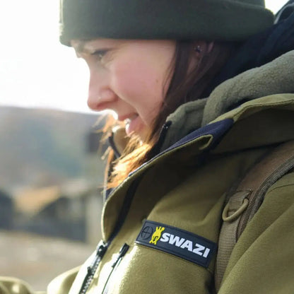 Woman in olive-green Swazi Artemis hunting jacket with SWAZI patch, perfect country clothing