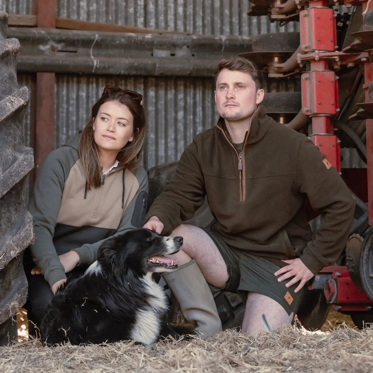 Two individuals and a dog posing in casual outdoor attire.