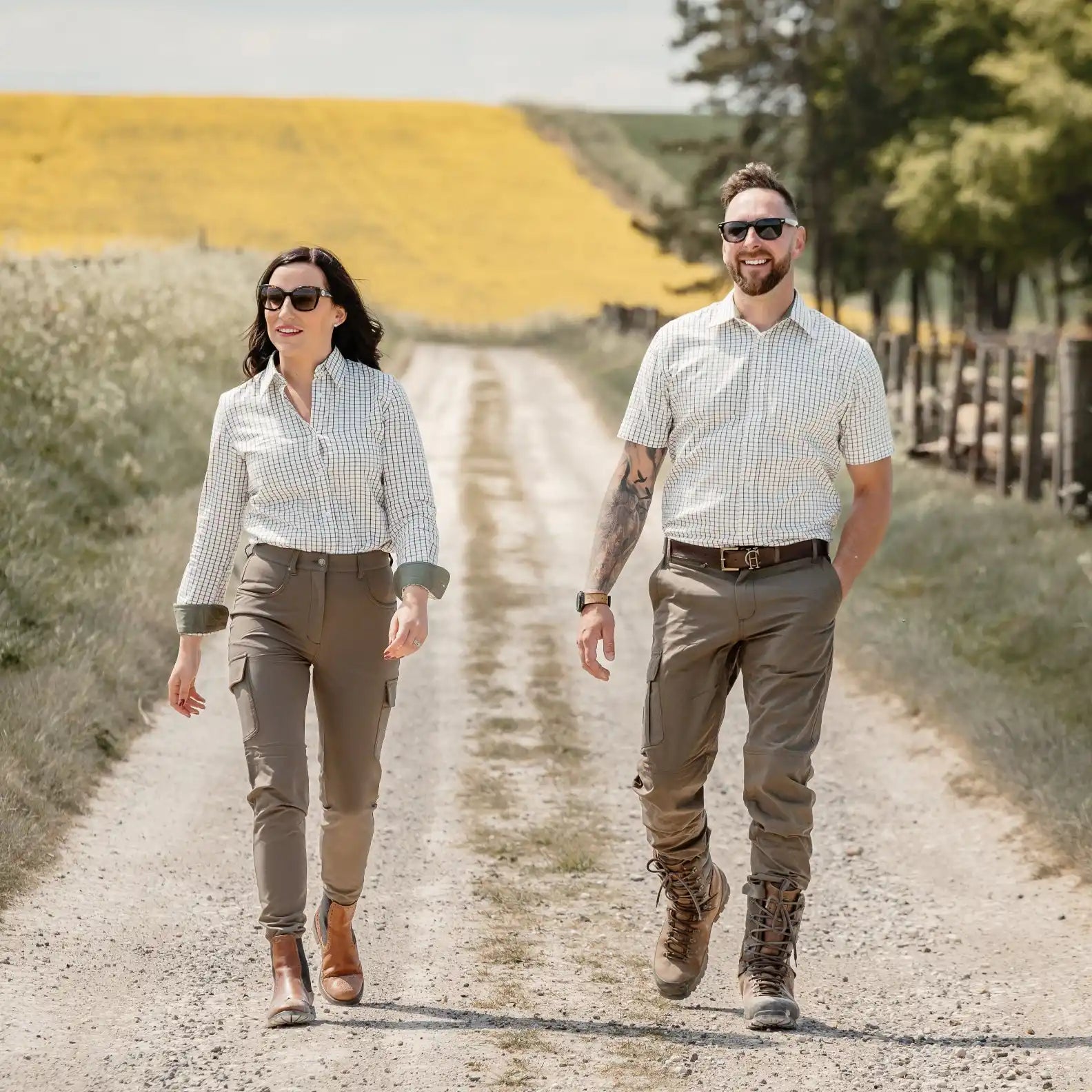 Two people wearing outdoor clothing walk on a dirt road.